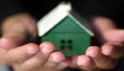 Close-up of hands holding a small model house.